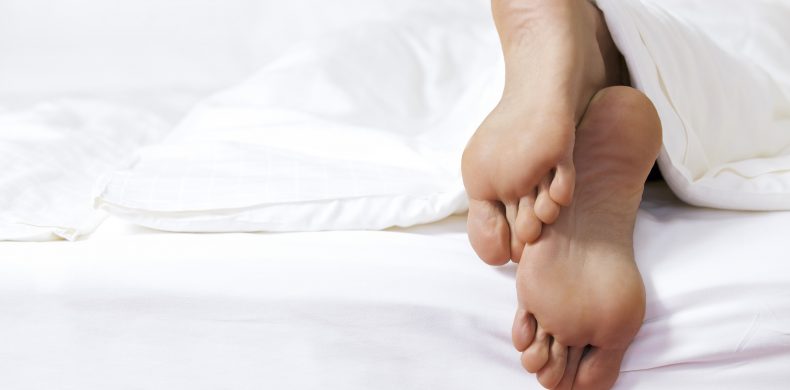 Person's foot in bed